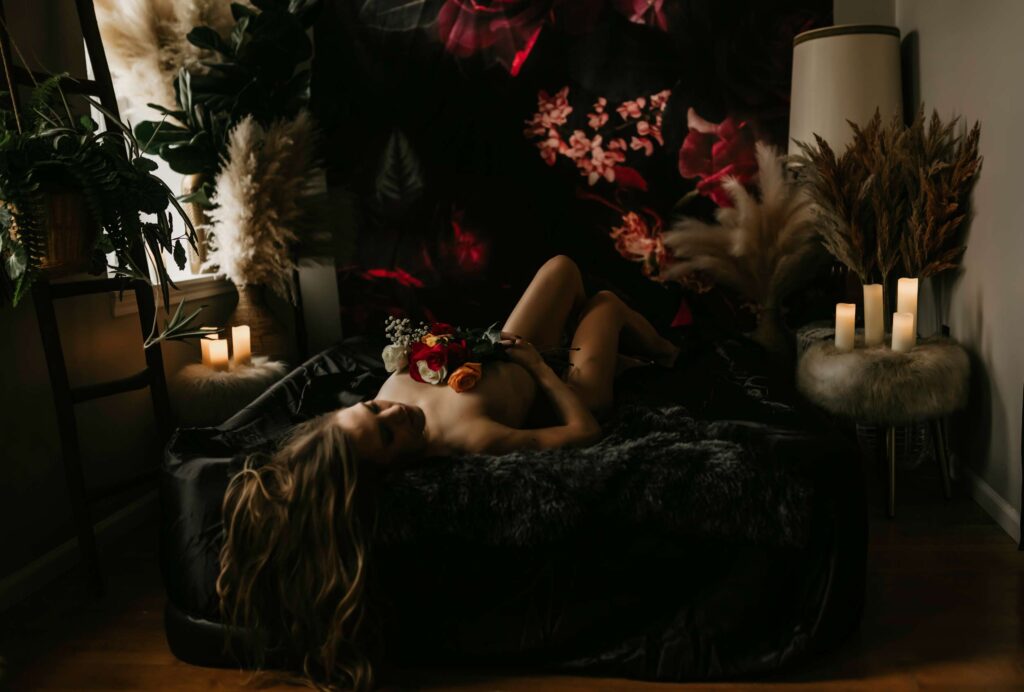 Person with flowers lies in dimly lit room.